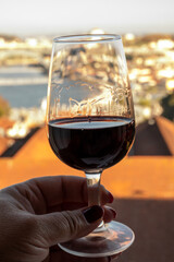 Tasting of different fortified dessert ruby, tawny port wines in glasses with view on Douro river, porto lodges of Vila Nova de Gaia and city of Porto, Portugal