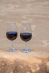 Tasting of different fortified dessert ruby, tawny port wines in glasses on sandy beach with view on waves of Atlantic ocean near Vila Nova de Gaia and city of Porto, Portugal