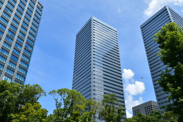 大阪ビジネスパークのビル群の上空を飛ぶ飛行機