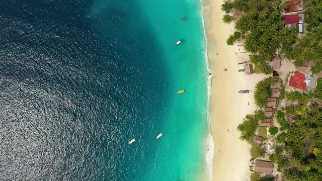 Aerial view huts on beach and turquoise water with boats on Asu Island, North Sumatra, Indonesia