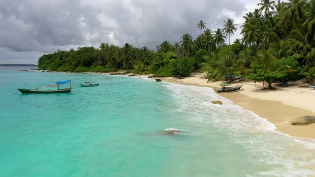 Drone flying along beach with amazingly blue water and palm trees at Asu Island, North Sumatra, Indonesia