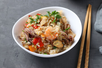 Fried rice with seafood, vegetables, ginger and parsley on dark background. Asian cuisine. Vegetarian food