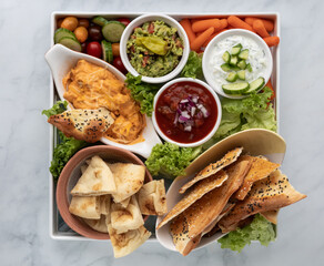 Top down view of a platter filled with various dips and breads and vegetables for dipping.