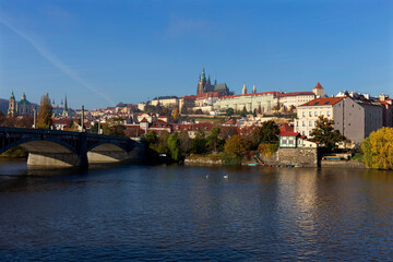 Autumn colorful Prague Lesser Town with gothic Castle above River Vltava in the sunny Day, Czech Republic