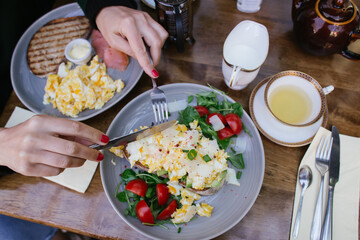 brunch or breakfast set up at a restaurant: 2 plates with sandwiches with avocado, eggs, salad, tomatoes, salmon and served with tea