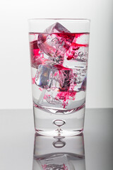 Red drops in water with ice cubes