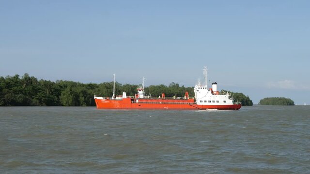 White Orange Color Cargo Barge on Green Trees Background. Transportation by sea concept