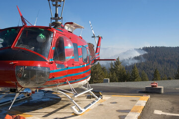 Fire fighting helicopter refueling, smoke in background.