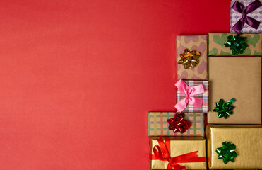 Decorated christmas concept with colorful ribbons gift boxes on red background.