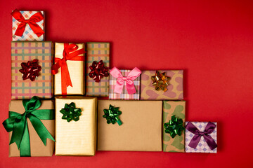 Decorated christmas concept with colorful ribbons gift boxes on red background.