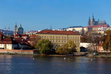 Autumn colorful Prague Lesser Town with gothic Castle above River Vltava in the sunny Day, Czech Republic