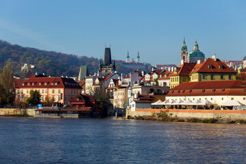Autumn colorful Prague Lesser Town with St. Nicholas' Cathedral above River Vltava in the sunny Day, Czech Republic