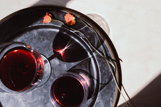 Red Wine Glasses On Tray In Afternoon Light With Dried Flowers