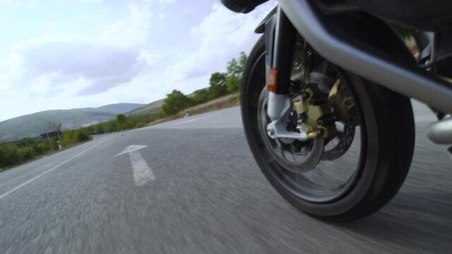 Motorcycle ridind on a road in nature. Close up wheel on a bumpy asphalt road. Recorded at 100 fps.