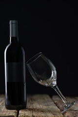 Bottle of red wine with empty glass on black background. Concept of alcoholic drink. Photo for advertising and product promotion. Space for text.