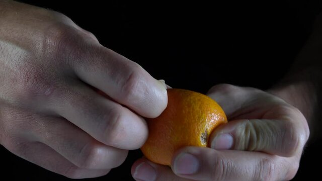 Mandarina mostrada a mano con plano en detalle con fondo negro en 4k de resoluci&oacute;n.