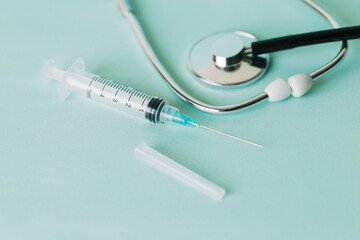 One single brand new sterile syringe next to a stethoscope