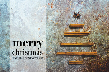 Christmas card with wishes. Merry Christmas and Happy New Year quote with nice minimalistic Christmas tree made of traditional spices (anise stars and cinnamon sticks) on the grunge, rusty background.