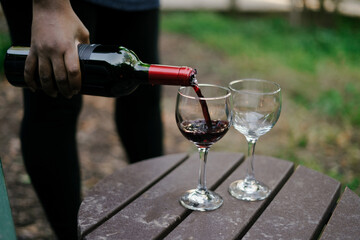 Black woman pouring a glass of wine at outdoor party