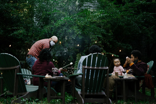 Black Friends Gathering Around Fire-pit Roasting Marshmallows And Eating Smores