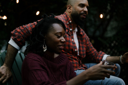 Black couple socializing and talking with friends at backyard party