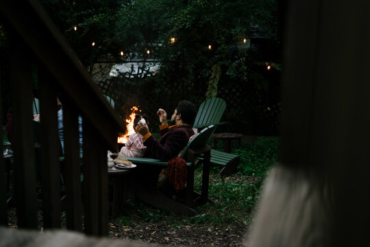 Friends gathered for evening party in backyard around firepit