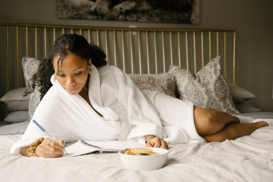 Black woman journaling at home in bed