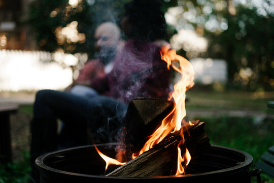 Friends together distanced at backyard party around firepit