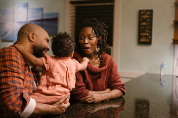 African American mom and dad laughing with daughter at home
