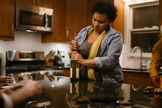 Woman Opening Wine Bottle At Party