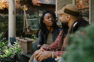 Beautiful black couple talking on front porch at home
