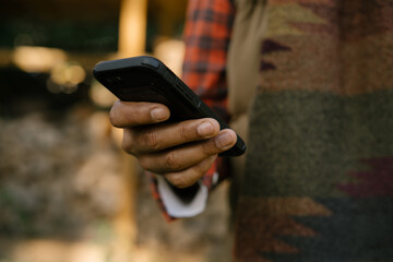 Black hand holding smartphone outdoors