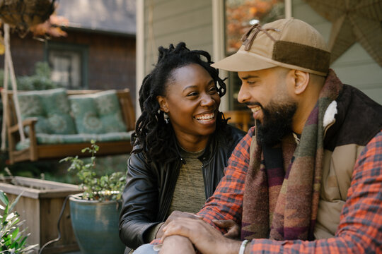Beautiful black couple talking on front porch at home