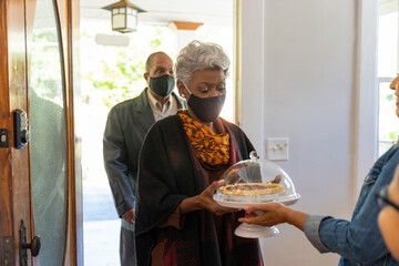 Grandmother and grandfather greet family for Thanksgiving wearing mask