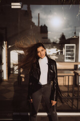 Obraz premium Beautiful girl along the street on the background of a cafe.
