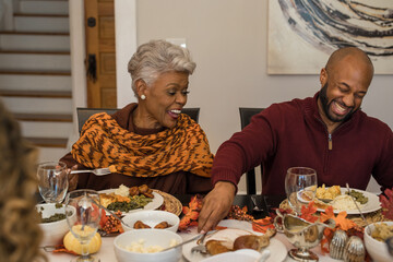 Multigenerational black family eating Thanksgiving dinner together at dining room table