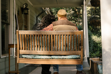 Black couple spending quality time together on front porch swing at home