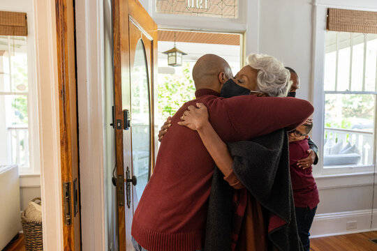 Grandmother And Grandfather Greet Family For Thanksgiving Wearing Mask