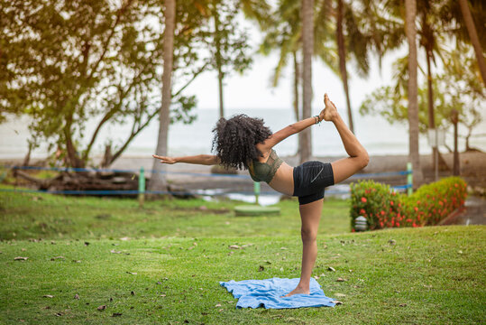 African American Woman Doing Yoga in a Green Area on the Beach