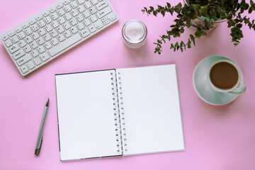 Cozy woman workplace with blank notepad, computer keyboard, cup of coffee and candle. Top view,...