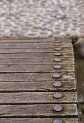 Old wooden boards of a bridge with round iron rivets.