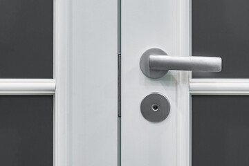 Closeup of metal doorhandle on wooden door.