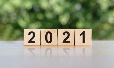 new year concept. font 2021 on wooden cubes on sunrise and bokeh green background