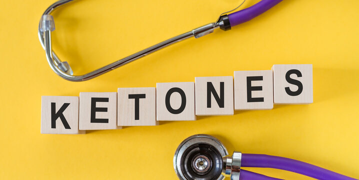 Ketones - word on wooden cubes on yellow background with stethoscope.