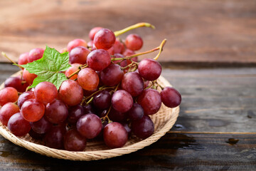 Fresh red grapes fruit in a basket on wooden background