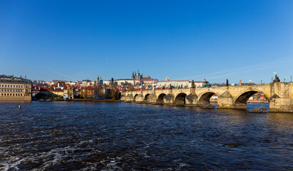 Autumn colorful Prague Lesser Town with gothic Castle and Charles Bridge above River Vltava in the sunny Day, Czech Republic