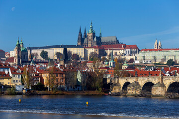 Autumn colorful Prague Lesser Town with gothic Castle and Charles Bridge above River Vltava in the sunny Day, Czech Republic