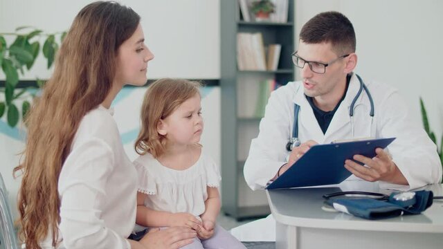 Male Doctor Pediatrician Examining an Ill Sad Kid at Medical Visit With Mother in the Hospital.Male Family Doctor Examining Ill Child.Talking With Doctor at Consultation During an Appointment
