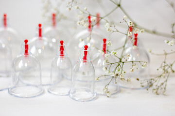 Jars for hijama on a white wooden background and white flowers. Bloodletting. Sunnah treatment. Islam.