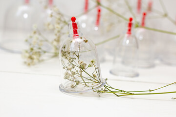 Jars for hijama on a white wooden background and white flowers. Bloodletting. Sunnah treatment. Islam.